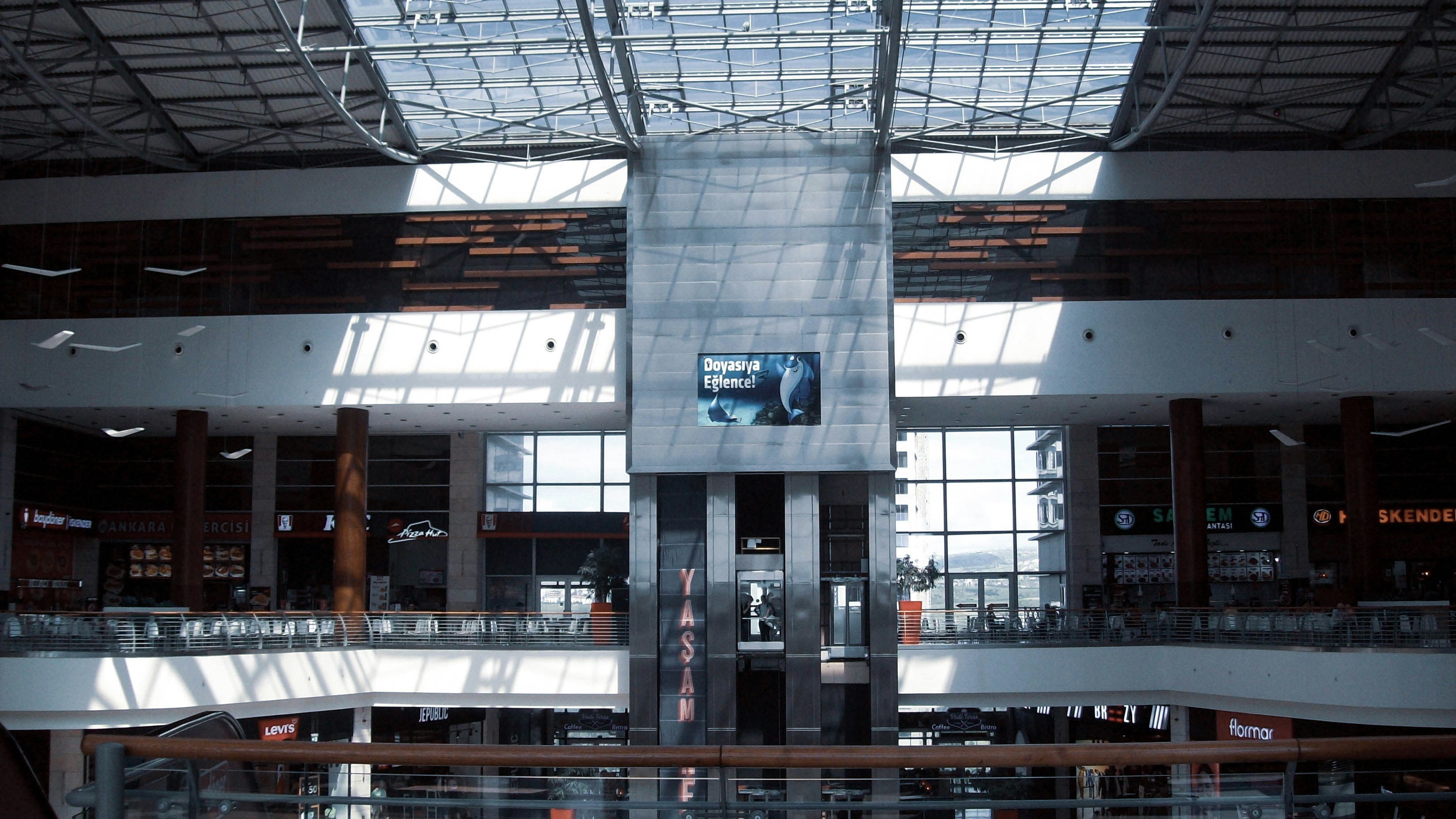 Bright airy shopping mall interior with wide corridors, natural skylights, modern retail storefronts, clean white surfaces