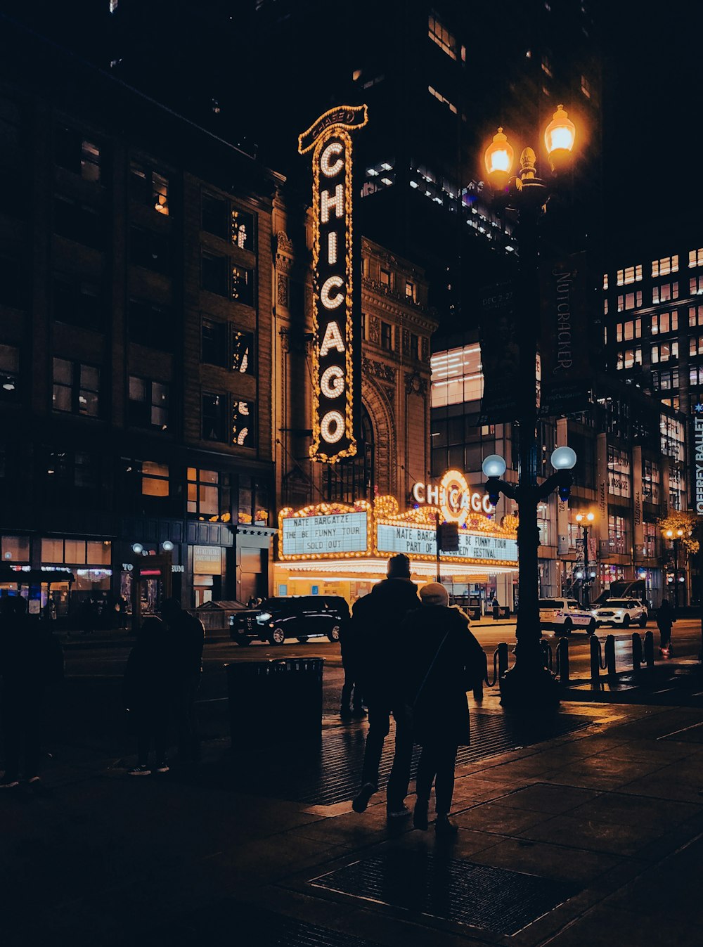 a couple of people walking down a street at night