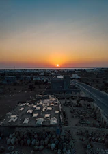 A vibrant sunset over a remote village where locals and travelers share stories around a campfire.