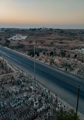Sunset view of the desert landscape near Tamgroute with pottery pieces arranged outdoors, highlighting their earthy tones.