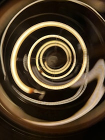 An abstract spiral of gold light flowing over a deep obsidian surface.