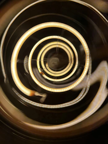 Close-up of golden wavy frequency mark logo glowing softly against a warm cream background with concentric golden arc rings.