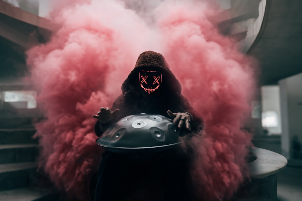 a man in a gas mask holding a helmet with smoke coming out of it