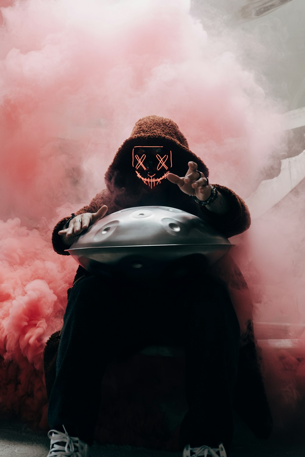 a person wearing a mask sitting in front of a cloud of smoke