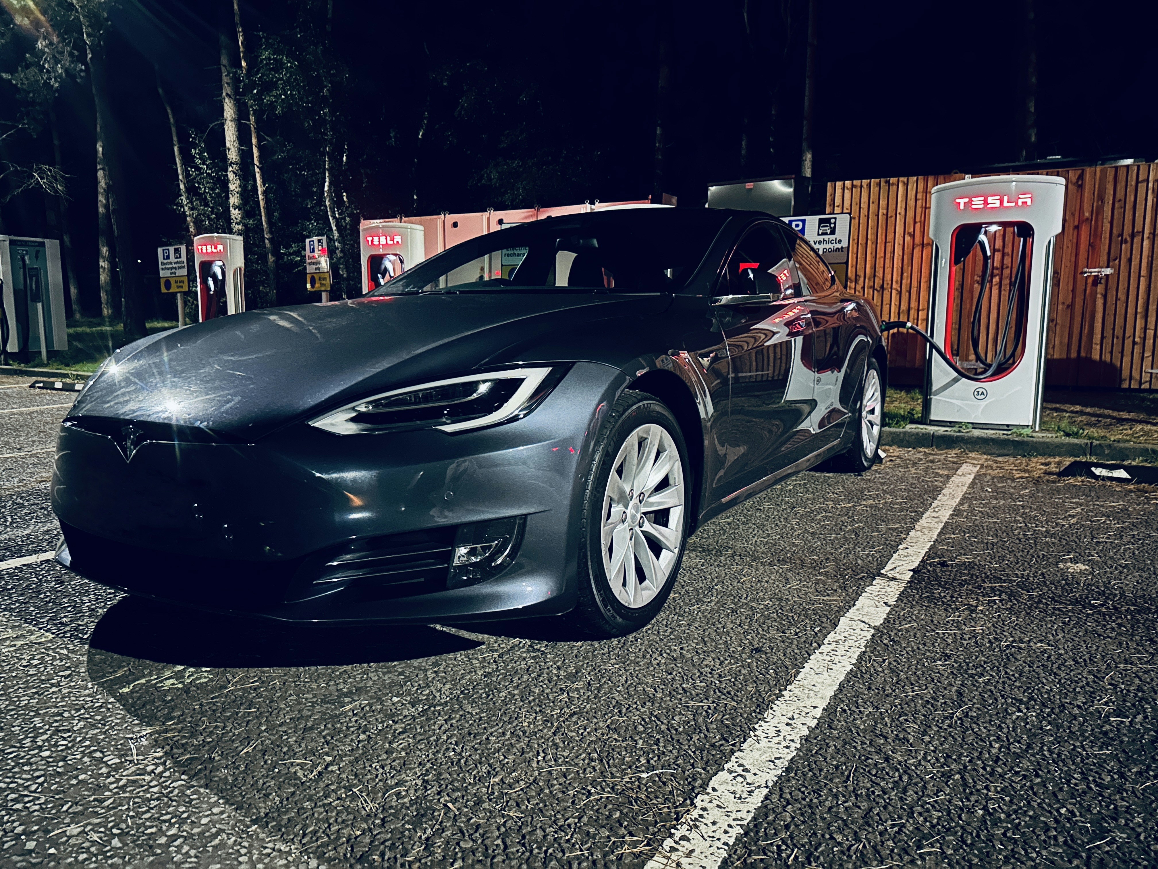 Tesla electric vehicle charging at supercharger station at dusk