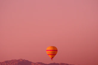 A colorful hot air balloon floating peacefully at sunset with warm orange hues.