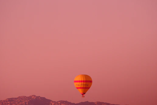 A colorful hot air balloon floating peacefully at sunset with warm orange hues.