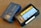 Two VHS-C video cassettes on a wooden surface. One is a Sony Premium 45 labeled case with blue coloring, and the other is a Fuji High Quality Plus HO+ EC-45 with a black casing and yellow label.