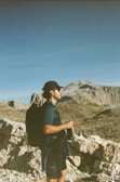 A hiker holding a Mendon Springs bottle against a backdrop of mountain peaks.