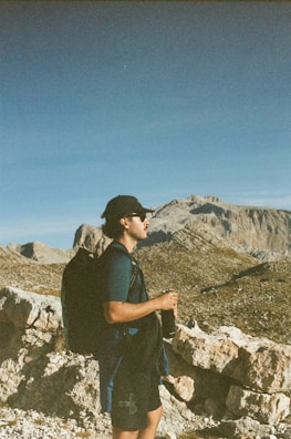 A hiker holding a Mendon Springs bottle against a backdrop of mountain peaks.