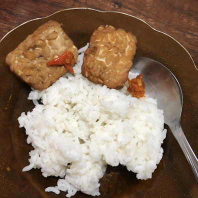 A plate of crispy, golden fried tempeh served with sambal chili sauce.