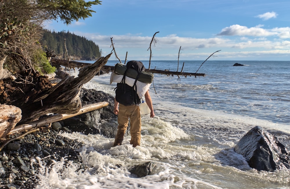 a man with a backpack walking into the water