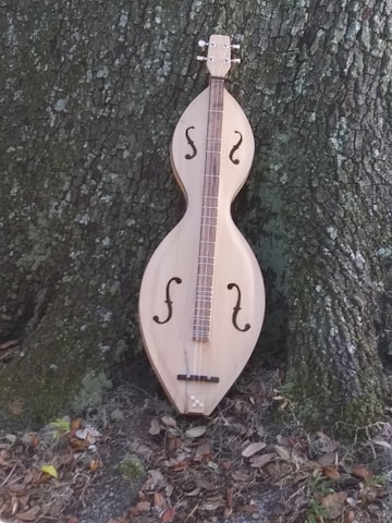 a wooden instrument sitting next to a tree