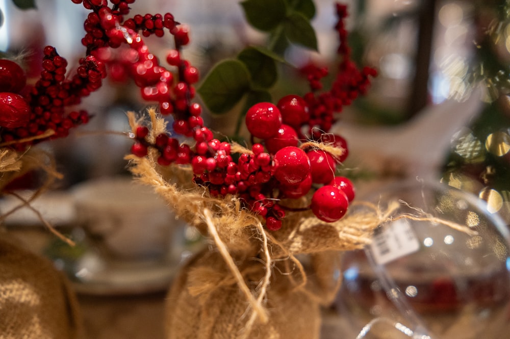 a vase filled with red berries on top of a table