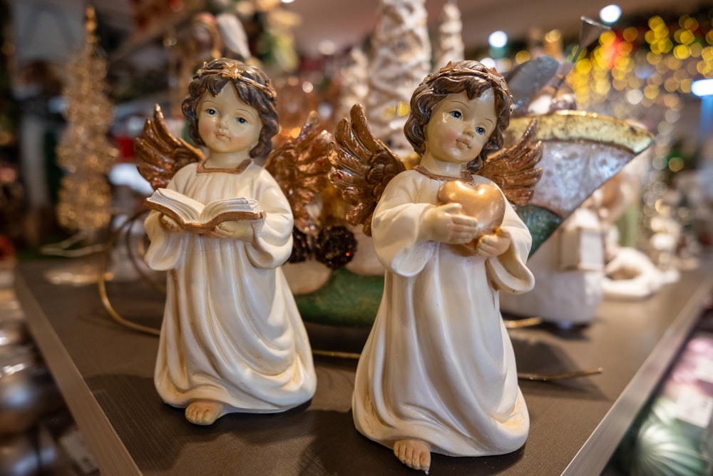 two angel figurines sitting on top of a table