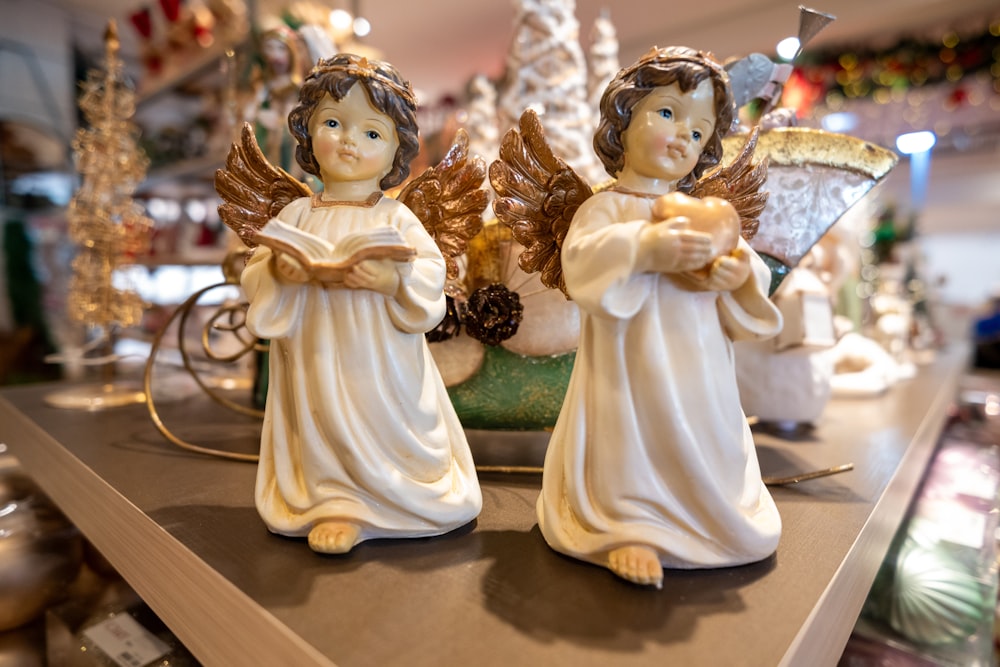 two angel figurines sitting on top of a table