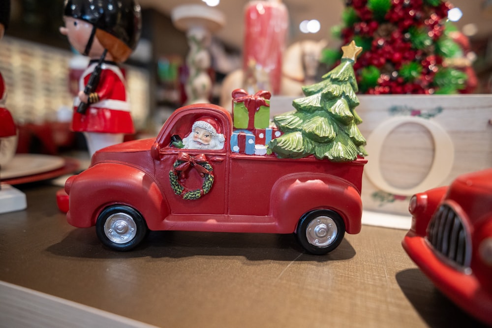 a red toy truck with a christmas tree in the back