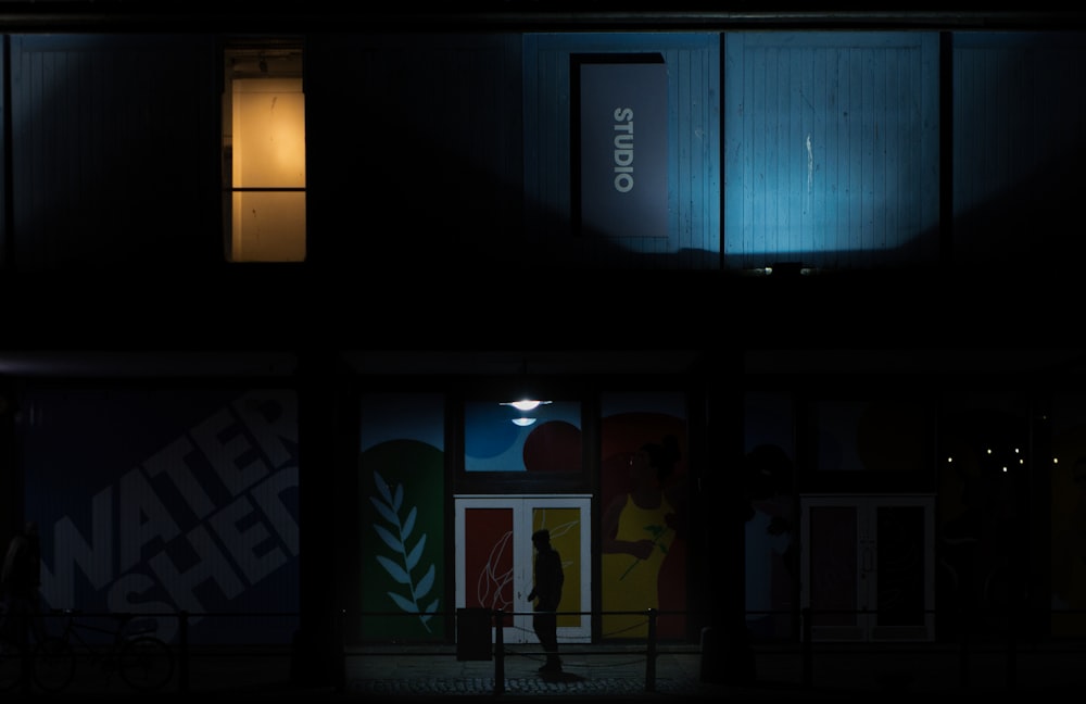 a building lit up at night with a person walking in the doorway