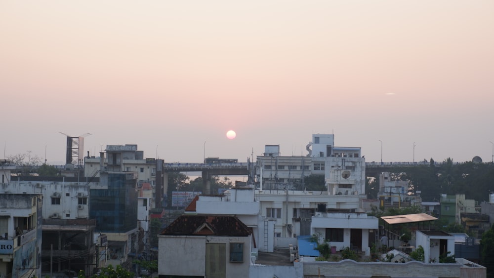 the sun is setting over a city with lots of buildings