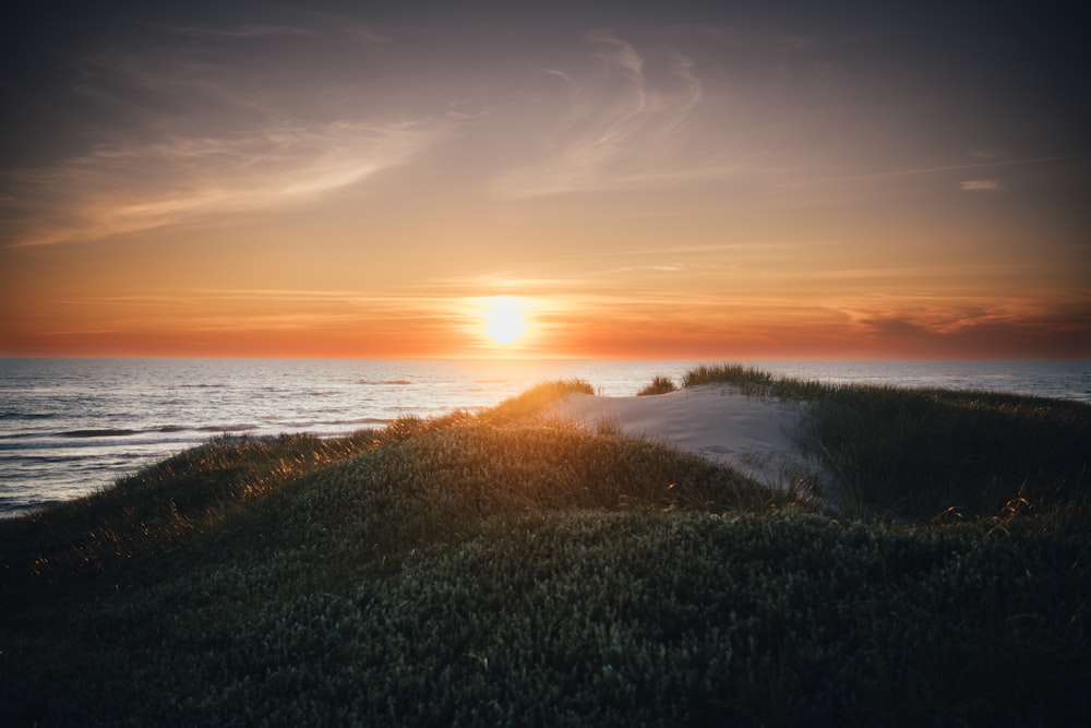 the sun is setting over the ocean on the beach