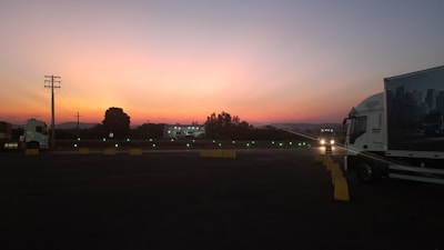 A well-lit truck parking facility with spacious stalls and a gated entrance at dusk.