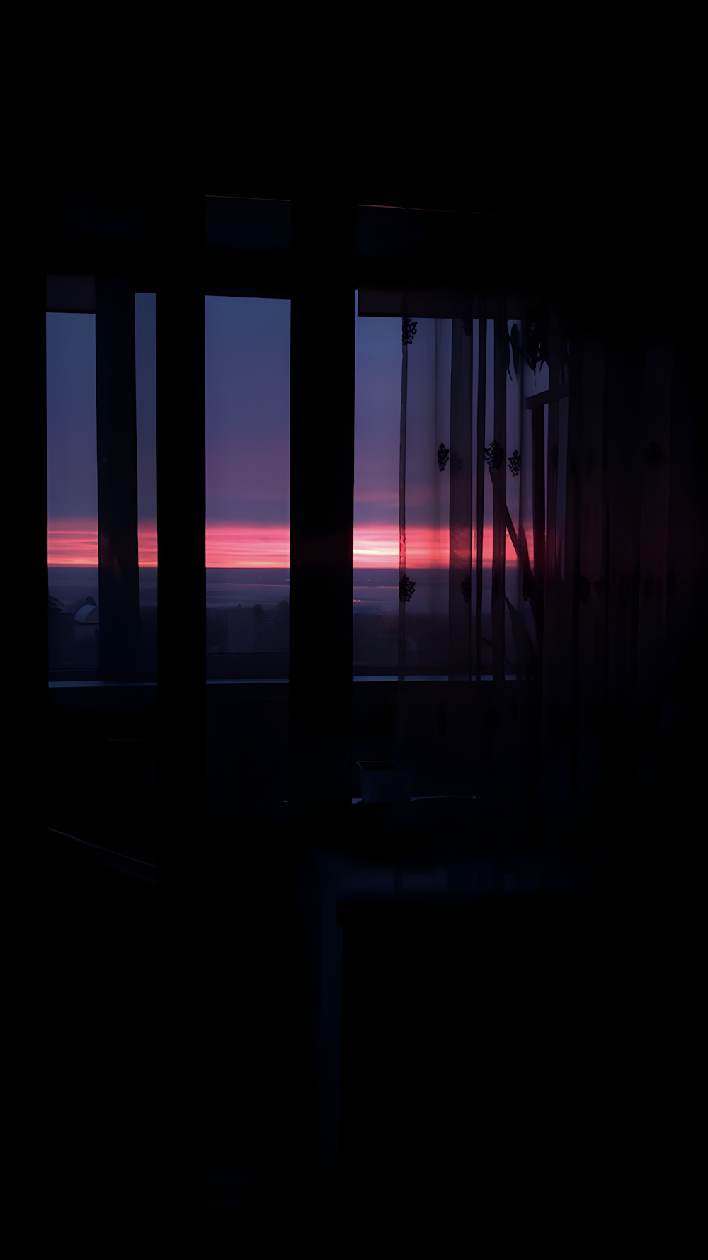 the sun is setting over the ocean from a window