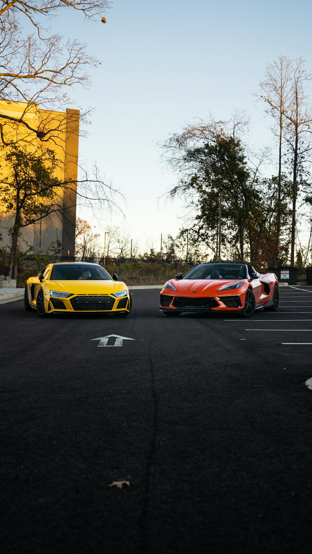 two orange and yellow sports cars parked in a parking lot