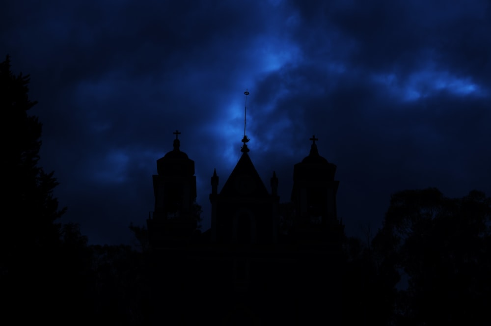 the silhouette of a church steeple against a dark sky