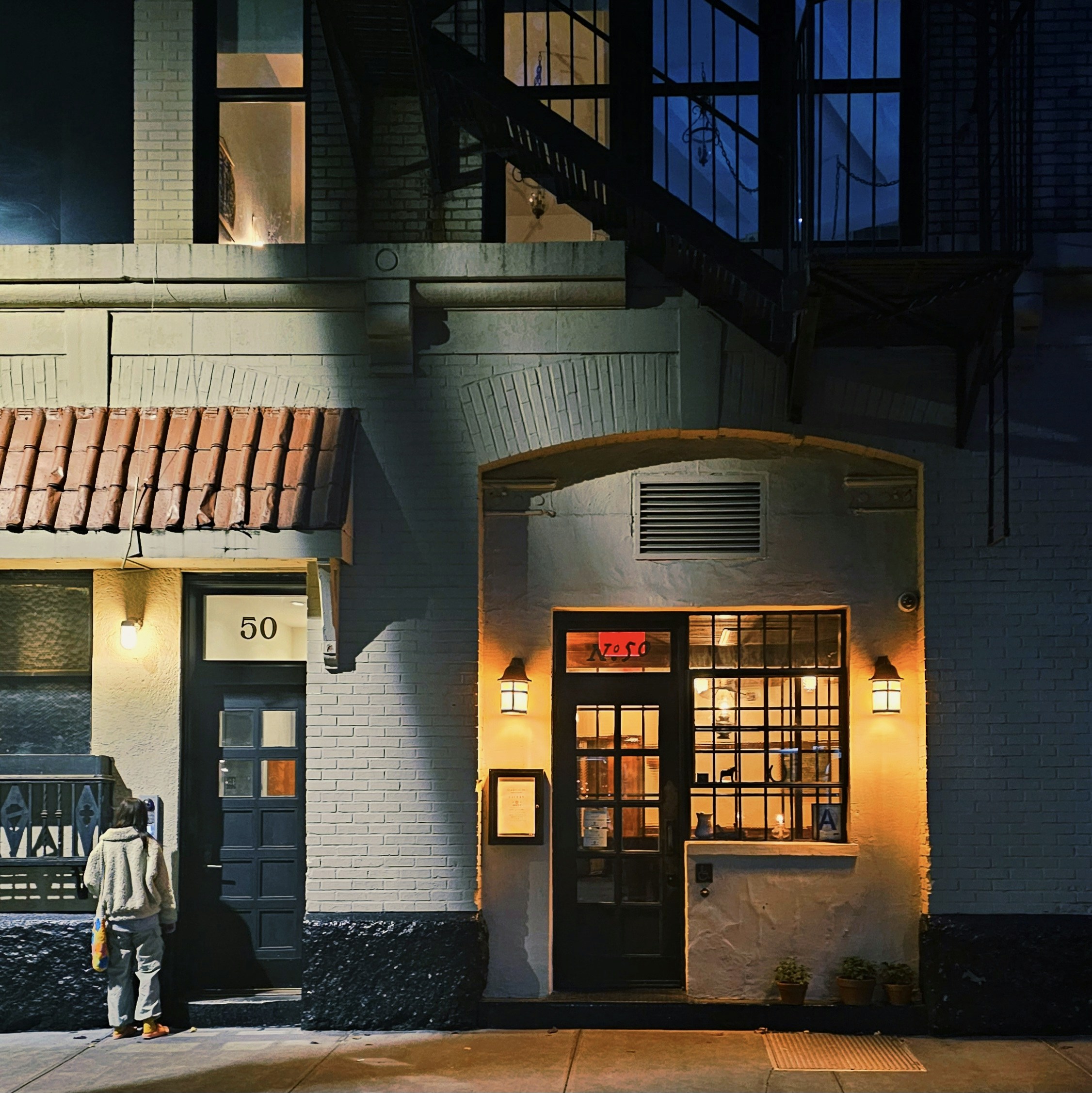 a man standing outside of a building at night