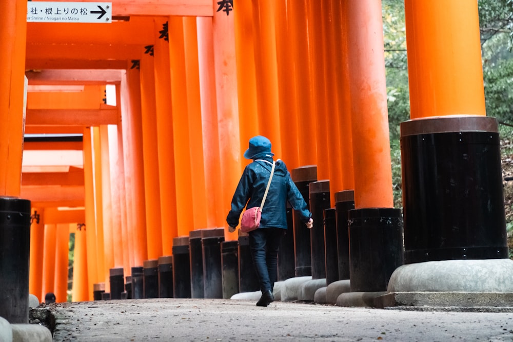 a person walking in front of a tall orange structure