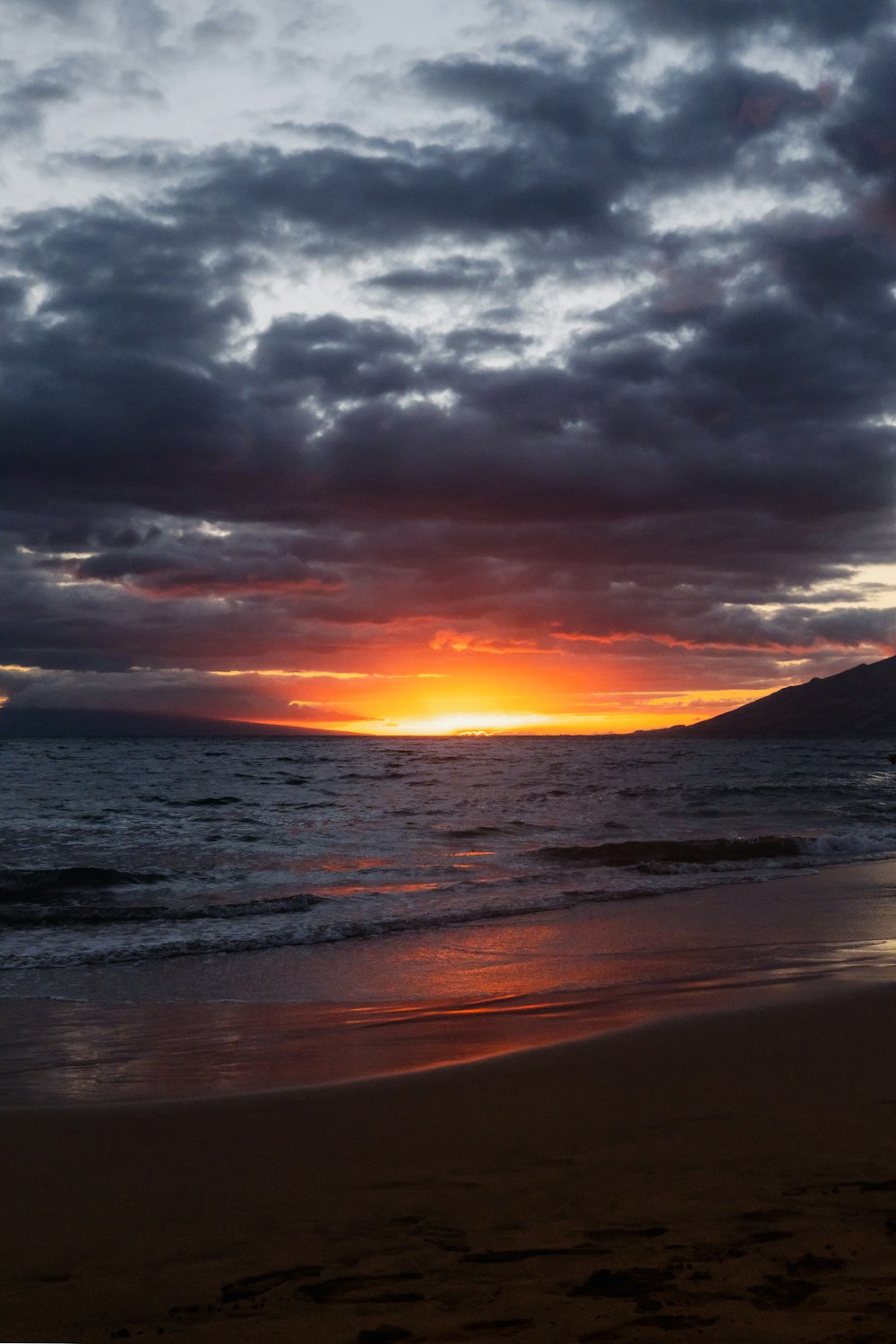 the sun is setting over the ocean on a cloudy day