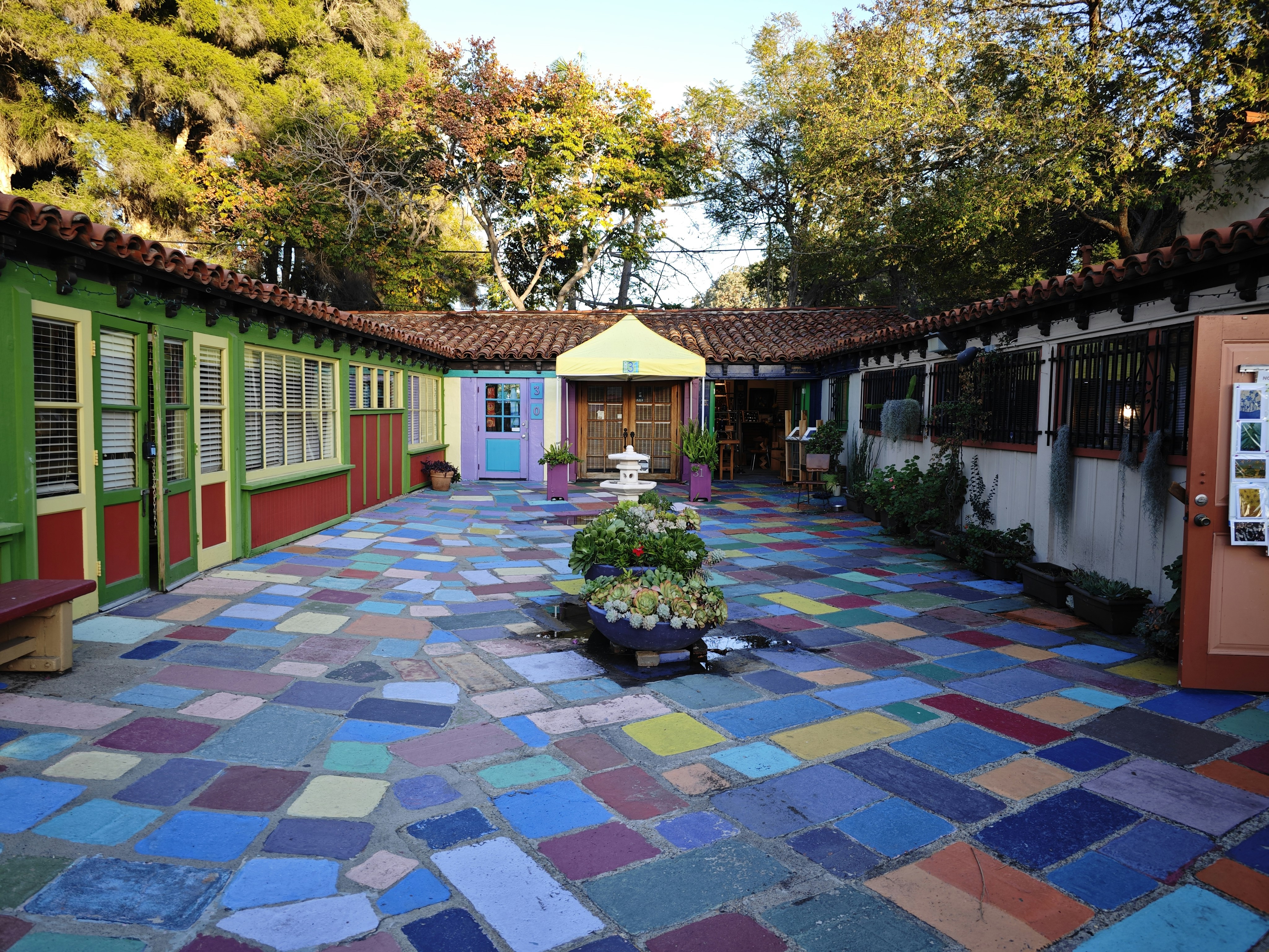 a colorful courtyard with potted plants in the center
