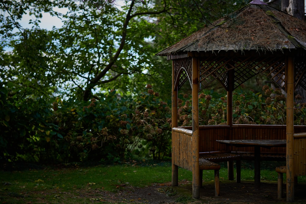 a gazebo with a table and bench in the grass