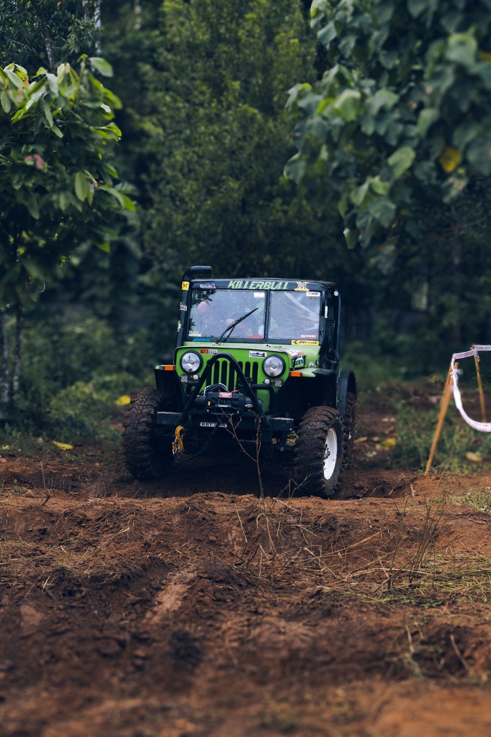 Ein grüner Jeep fährt eine unbefestigte Straße entlang