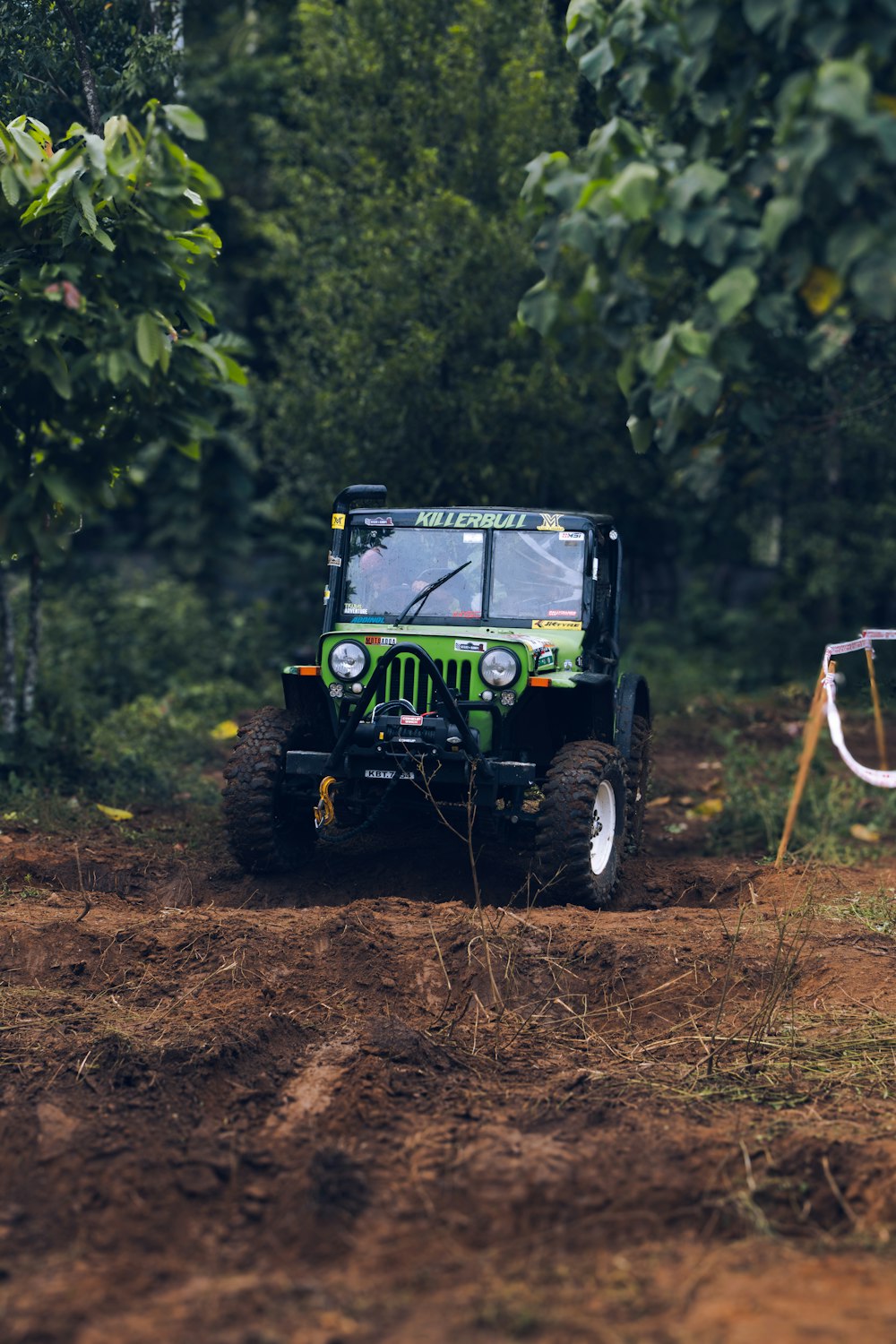 a green jeep driving down a dirt road