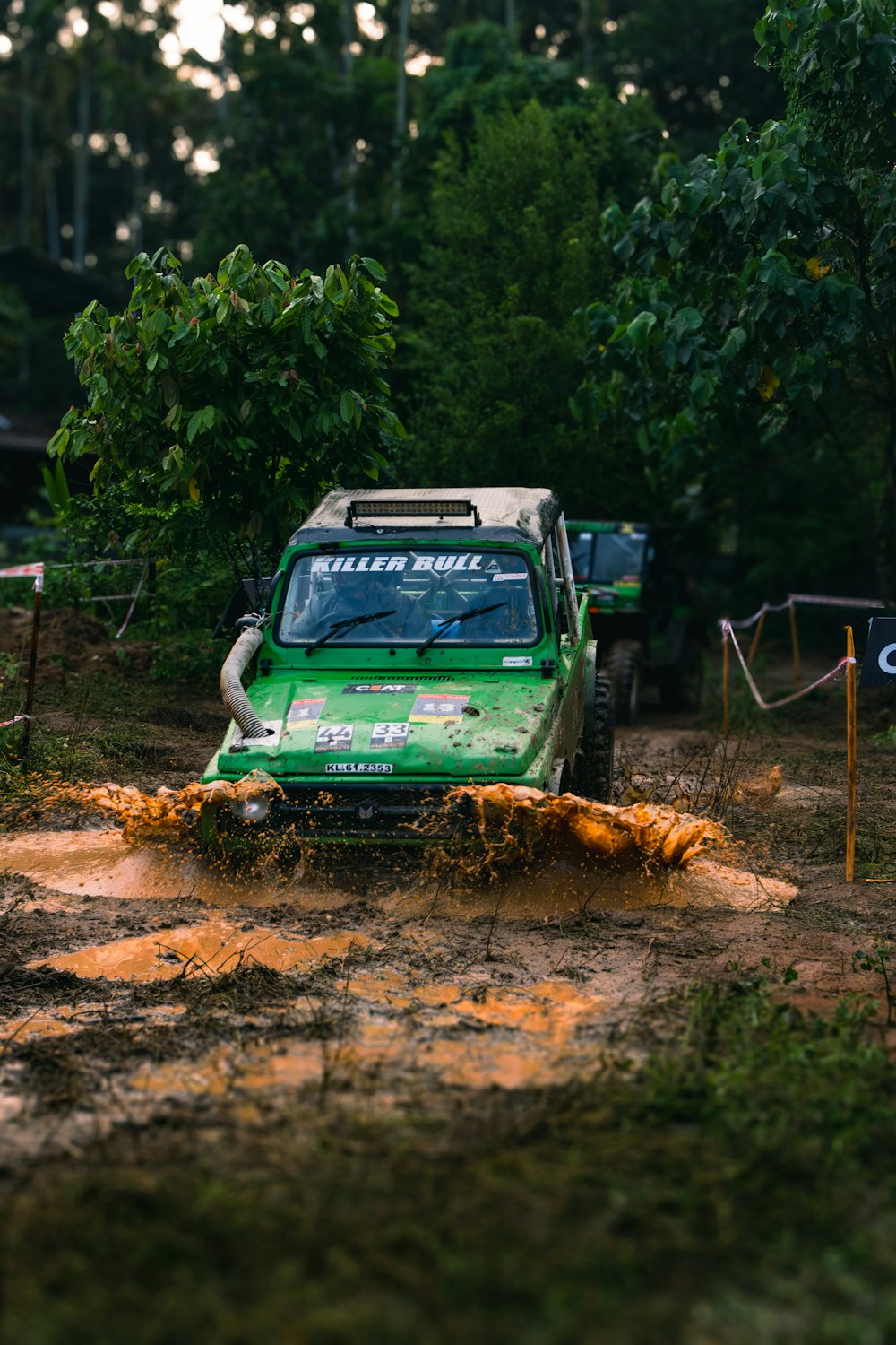 a green truck driving down a muddy road