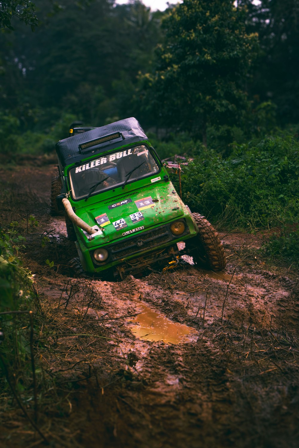 a green truck driving down a muddy road