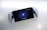 A handheld gaming device is positioned against a white background. The device features a screen displaying a PlayStation logo with the prompt 'To unlock, press the PS button.' It is framed by white controllers on both sides, resembling a hybrid of a tablet and a console.