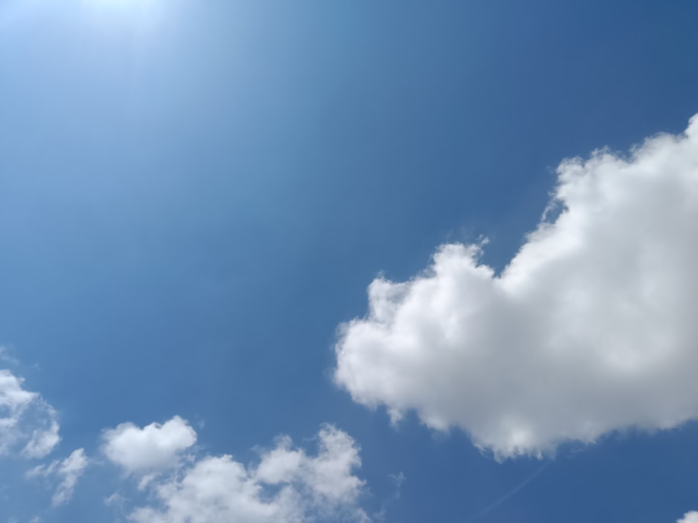 a plane flying through a blue sky with clouds