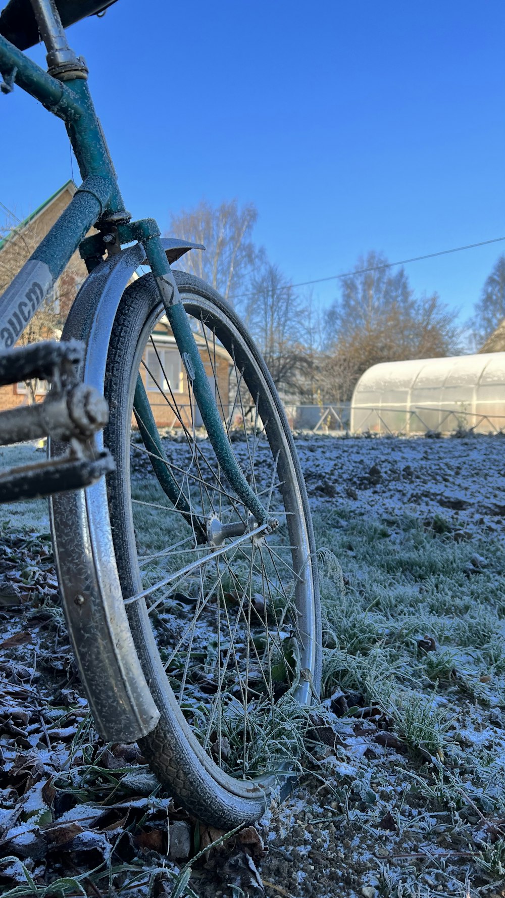 an old bicycle parked in a field covered in ice