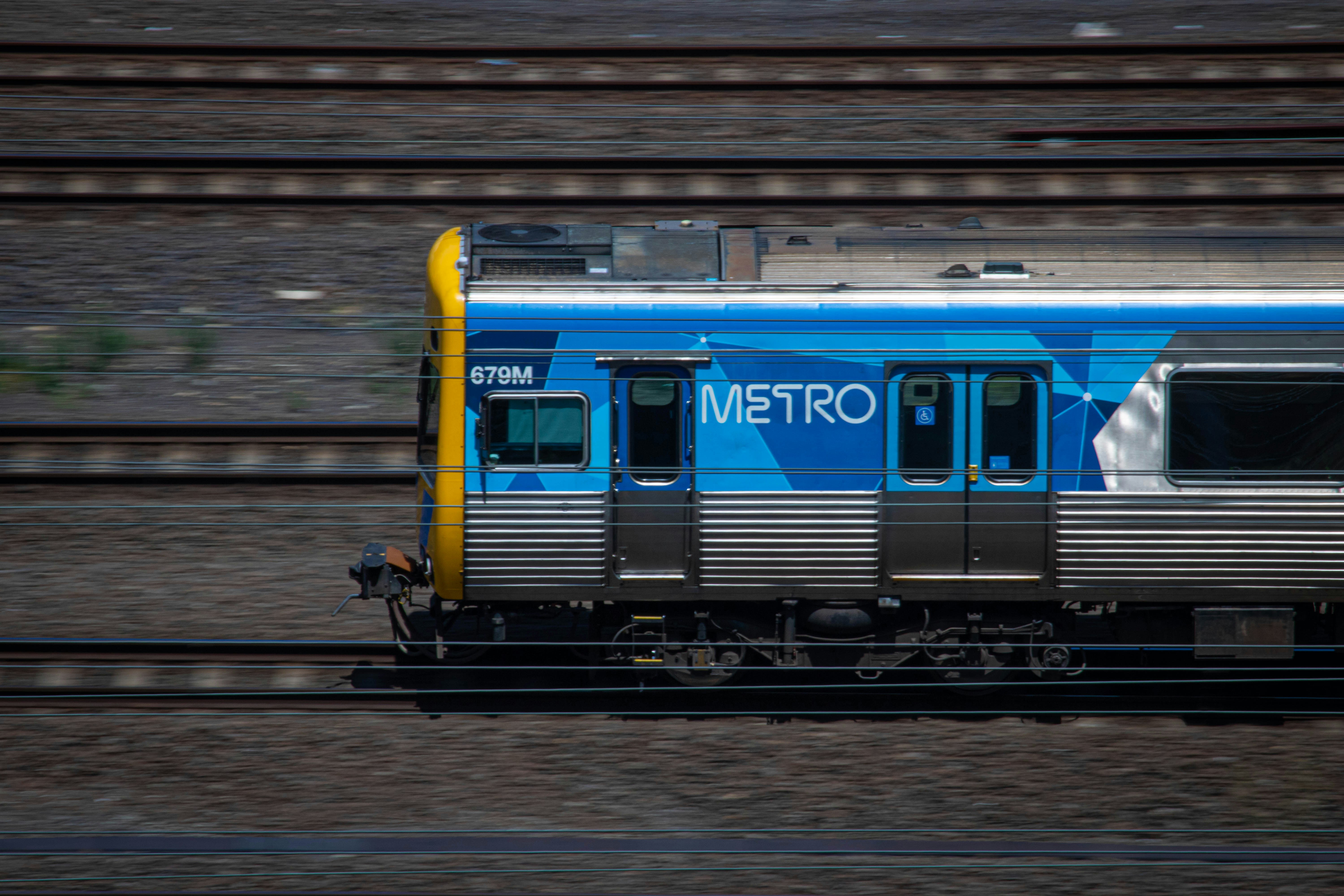 a blue train traveling down train tracks next to a forest