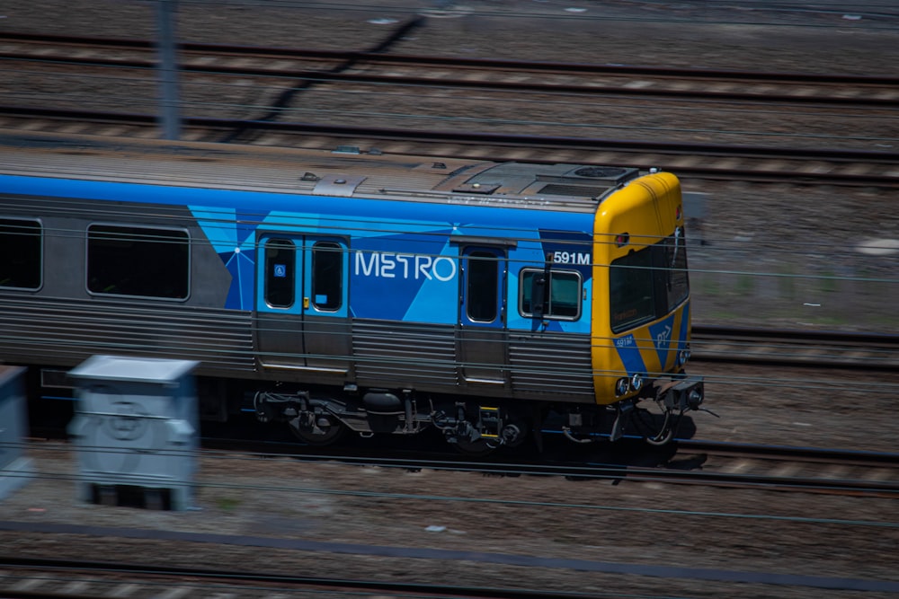 a blue and yellow train traveling down train tracks