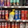 A variety of snack containers are neatly arranged on supermarket shelves. The products include cans of Pringles chips in different flavors such as BBQ, Original, Salt & Vinegar, Habanero, and Scorchin' Sour Cream & Onion. A yellow bag of chips is placed between the cans. Also visible are Doritos Minis Nacho Cheese containers. Prices are displayed on tags below each row.