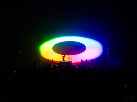 A vibrant stage setup with colorful lights and a lively audience at a cultural event.