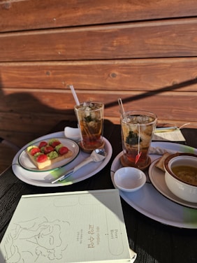 A cozy corner of 120 Ages with sunlight filtering through, showcasing steaming herbal tea and fresh salads.