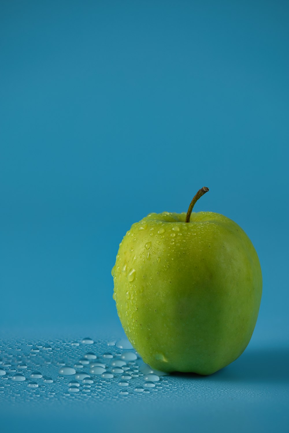ein grüner Apfel, der auf einer blauen Oberfläche sitzt