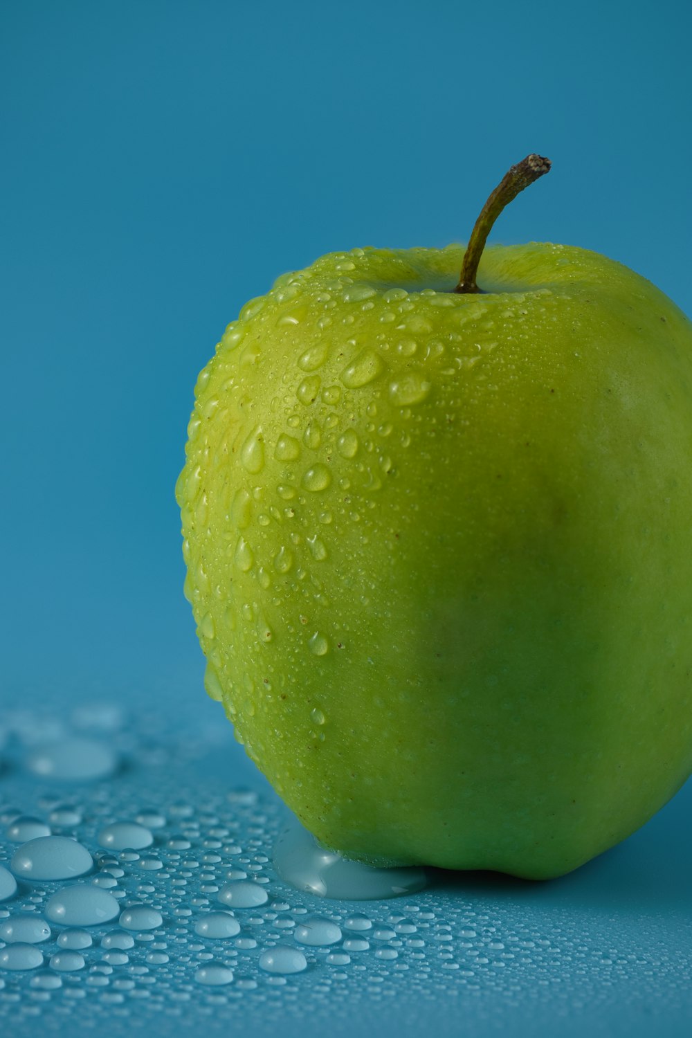 ein grüner Apfel, der auf einer blauen Oberfläche sitzt