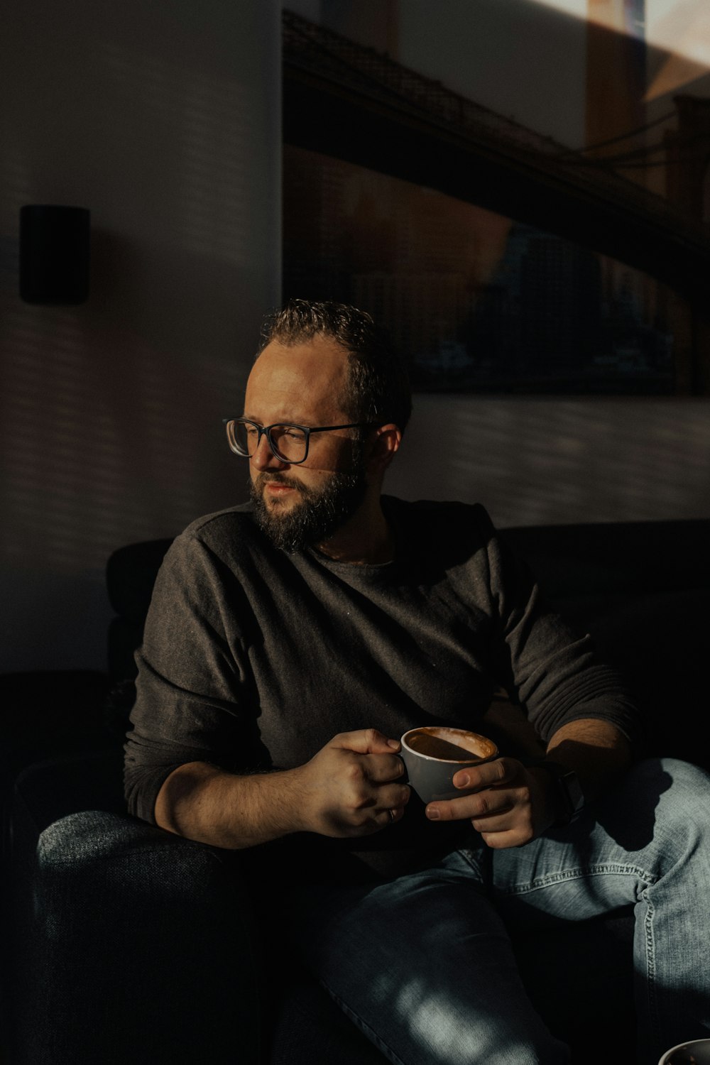 a man sitting on a couch holding a cup of coffee