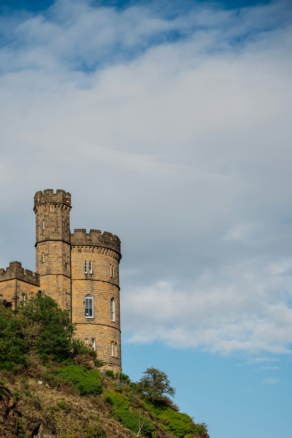 a tall castle sitting on top of a lush green hillside