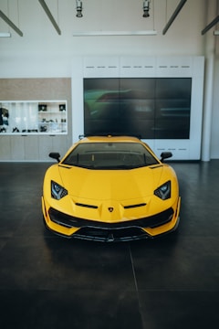 A minimalist showroom with black walls and neon-yellow accents highlighting a luxury car.